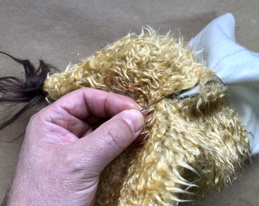 A puppet maker hand-stitching curly fabric